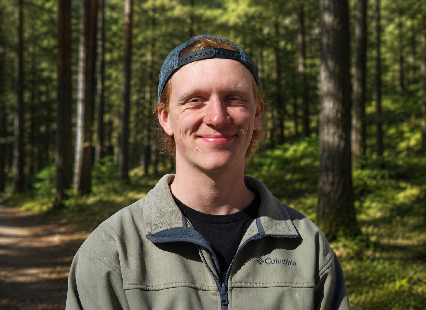 Oskar Holmlund, biology student, in a sunlit pine forest